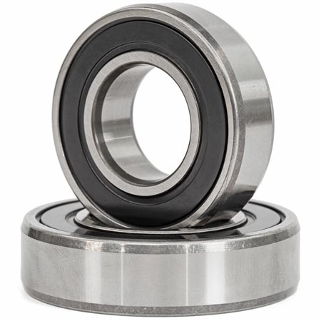 Close-up of two metal ball bearings, one standing upright and one lying flat, with visible inner and outer rings and a smooth, polished steel finish.