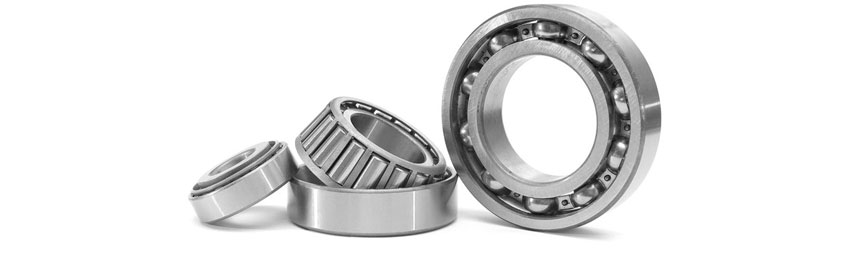 Close-up of three metal bearings, including a ball bearing and a tapered roller bearing, arranged on a light background with polished steel surfaces visible.